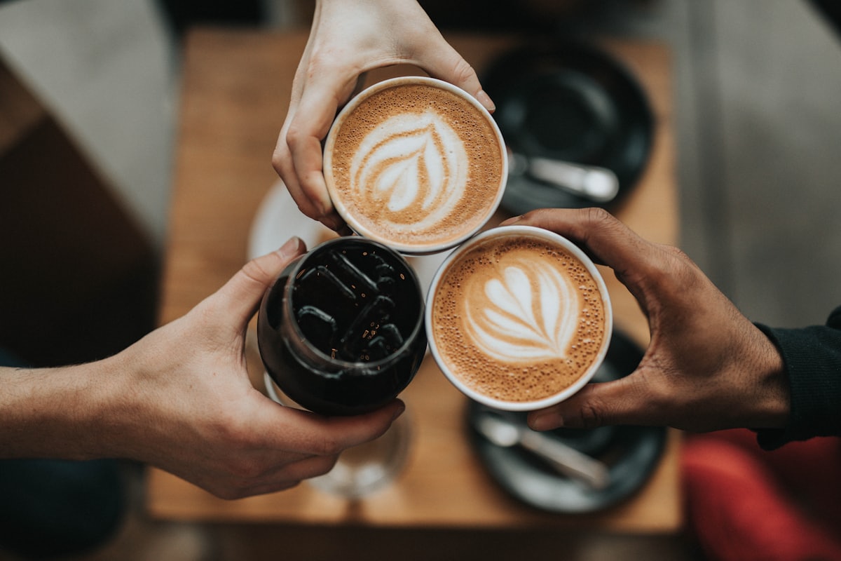 A freshly poured latte in a ceramic cup beside coffee beans